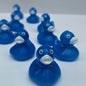A row of small blue rubber ducks with white beaks and black eyes arranged diagonally against a plain light gray wall.